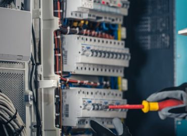 Man, an electrical technician working in a switchboard with fuses. Installation and connection of electrical equipment.